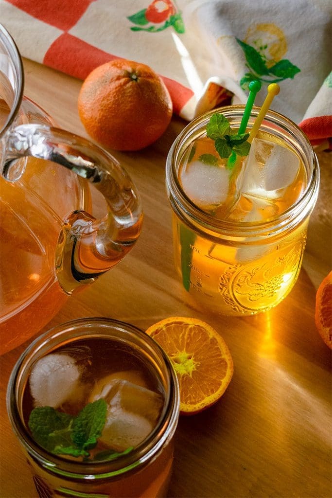 glass of sunshine tea on table next to pitcher in sunlight
