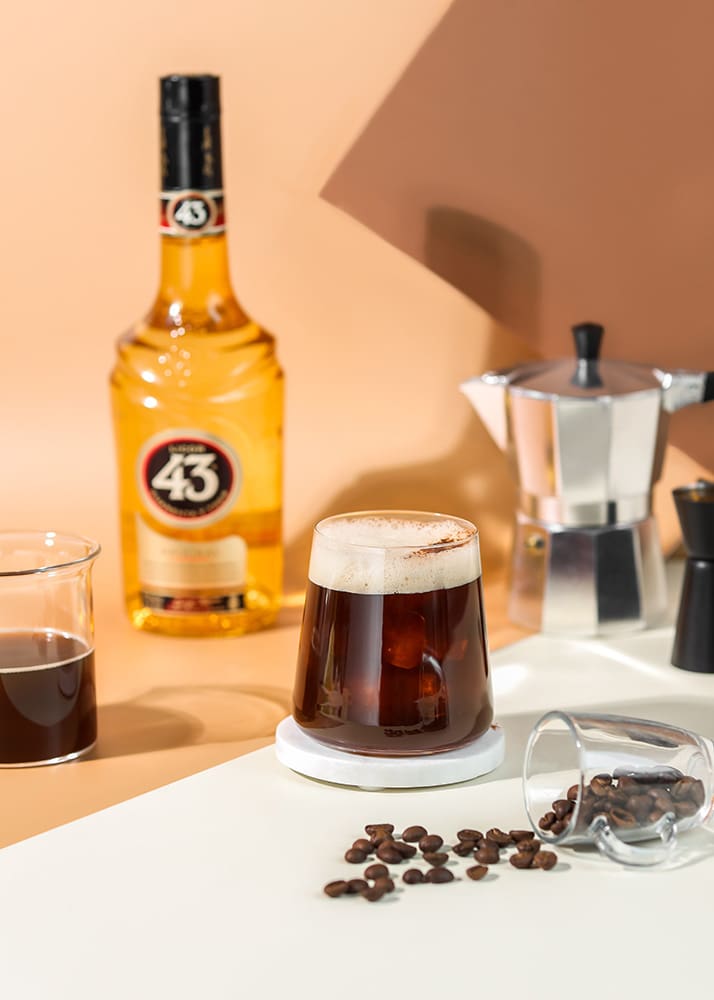 Carajillo coffee in cup next to liquor and coffee beans