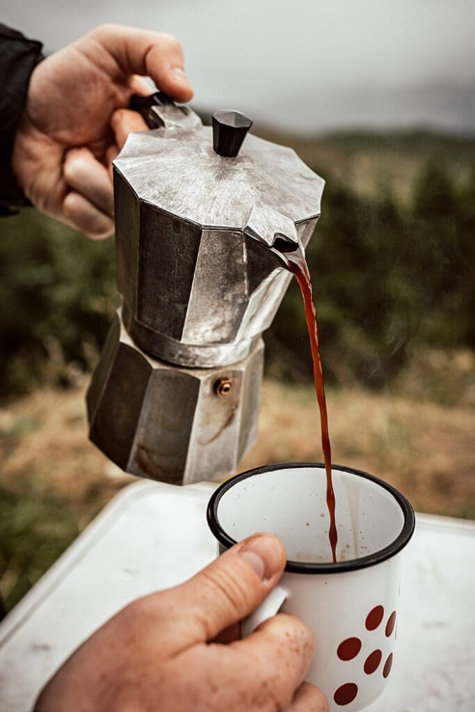 pouring coffee into a mug from a moka pot
