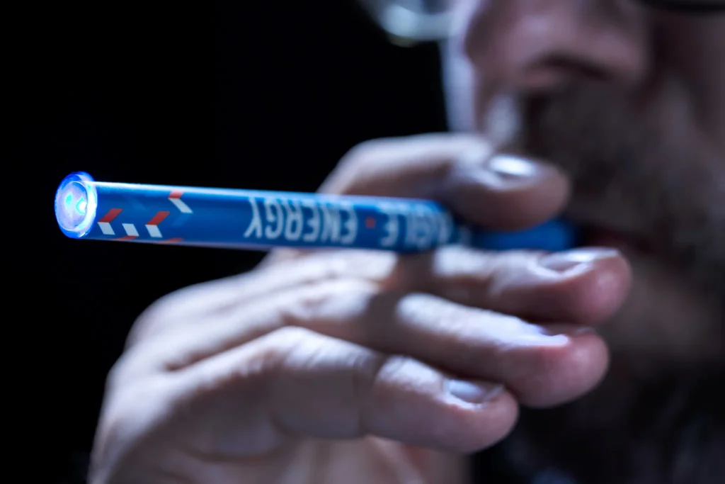 Caffeine Inhalers: An In-Depth Look at Use, Effects, and Regulation A man vaping with blue Eagle Energy Caffeine Inhalers