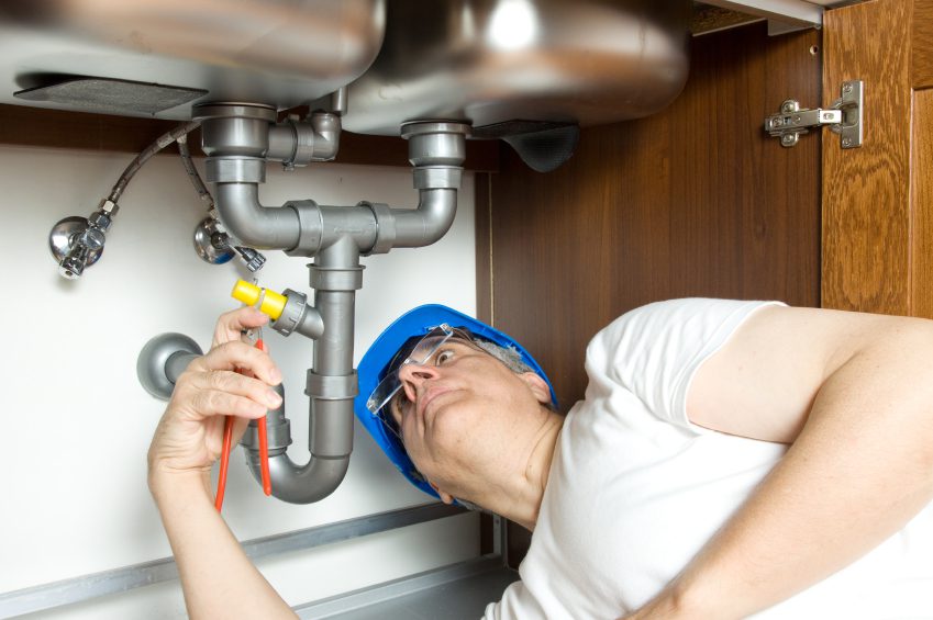 Professional Plumber Under A Sink