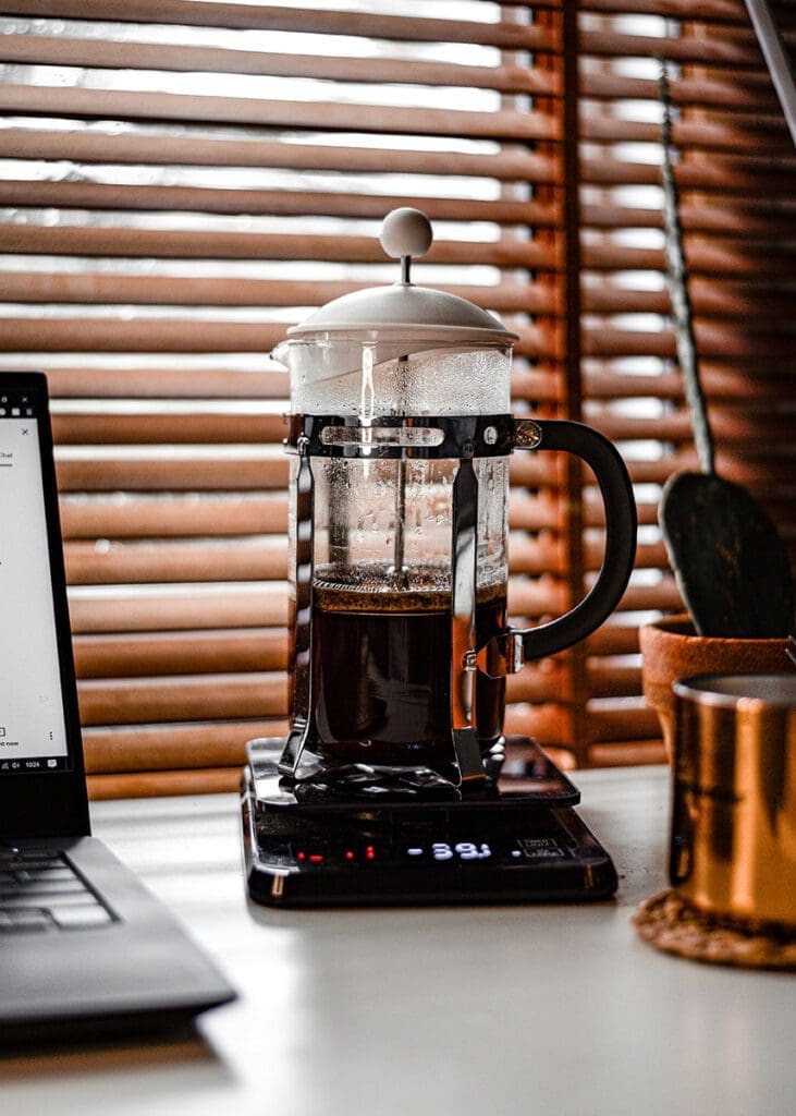 A french press brewing coffee on a scale in a kitchen