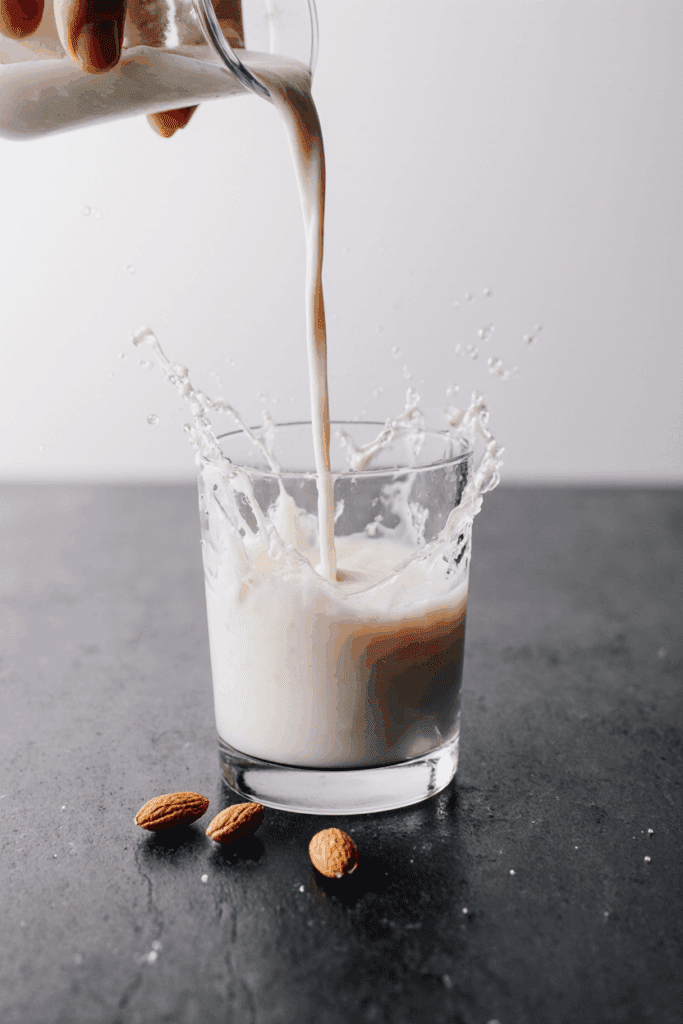 Does McDonald’s Have Almond Milk for Coffee? Complete McCafé Dairy-Free Guide 2025 Does McDonald’s Have Almond Milk for Coffee – almond milk splashing into a glass with whole almonds nearby