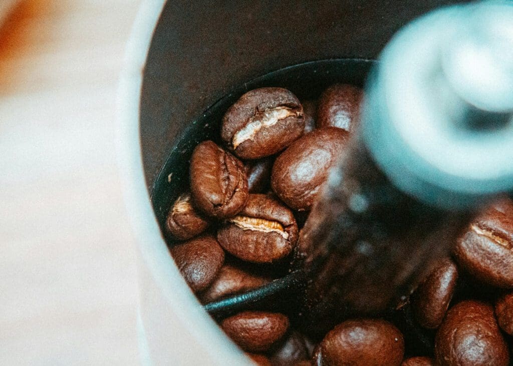 coffee beans in a coffee grinder, Is Grinding Your Own Coffee Cheaper