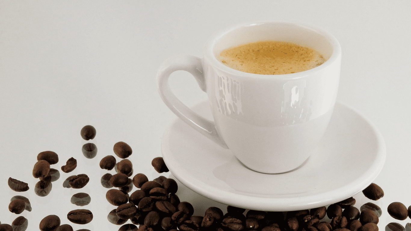 Why Cuban Colada Will Hit You Harder Than an Espresso Shot Ever Should A cup of Cuban colada coffee with light crema, surrounded by roasted coffee beans.