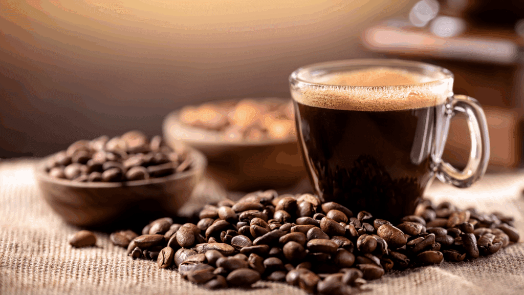 Glass cup of Brazil's bourbon peaberry coffee on burlap with scattered beans.