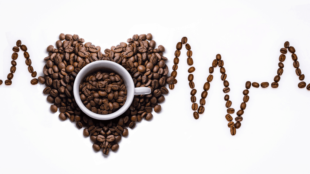 Coffee cup in heart-shaped bean arrangement with EKG-style lines.