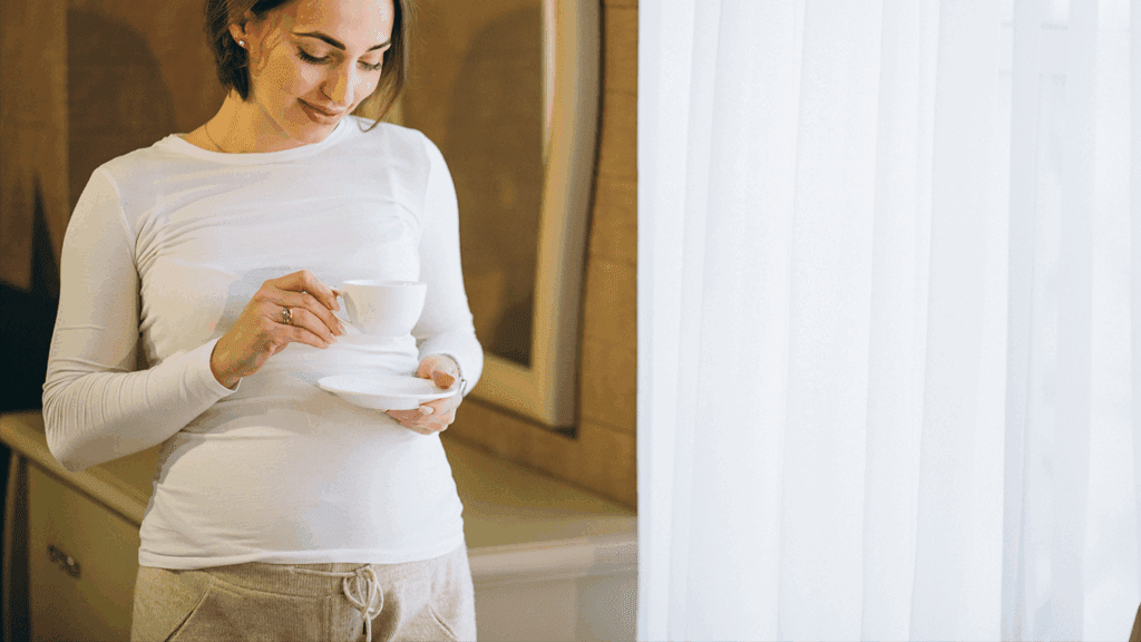 Pregnant woman holding a coffee cup.