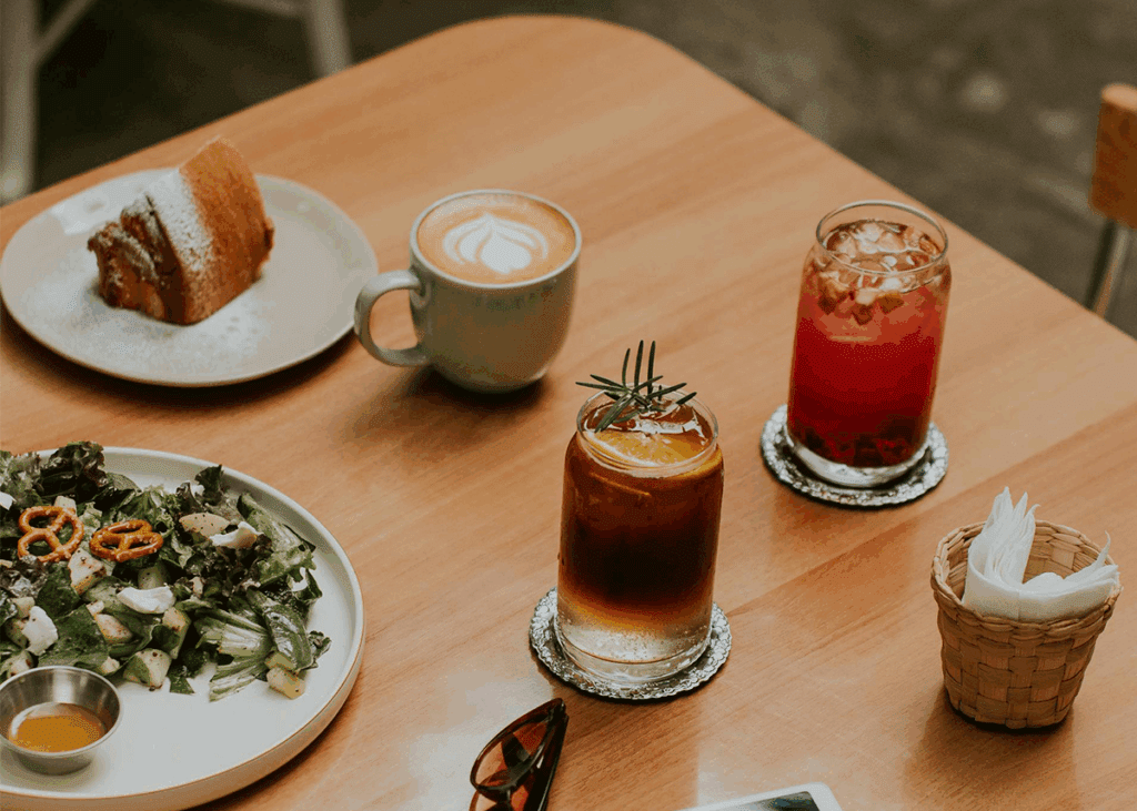 How Much Coffee Is Safe During Pregnancy? Table with coffee, soda, juice, salad, and dessert.