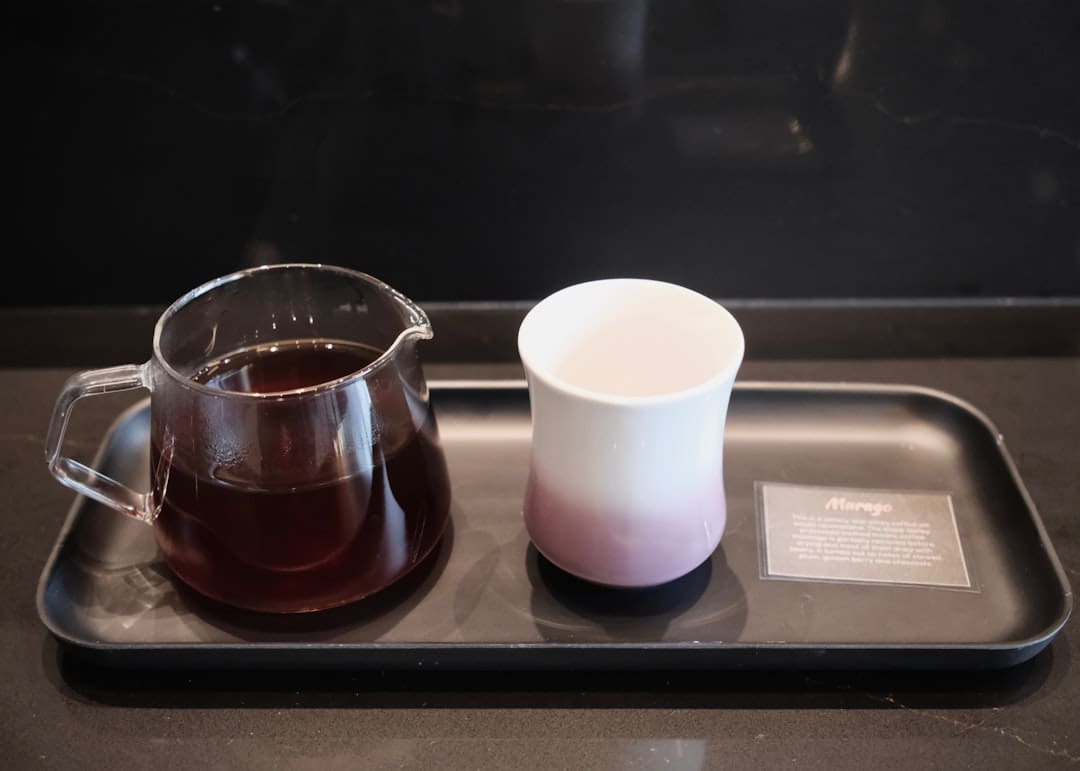 Glass pitcher with coffee and empty cup on tray