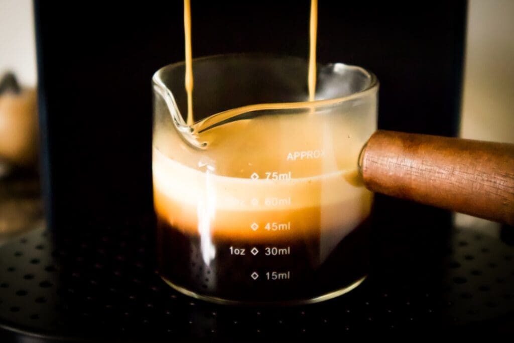 Espresso being poured into a glass beaker.