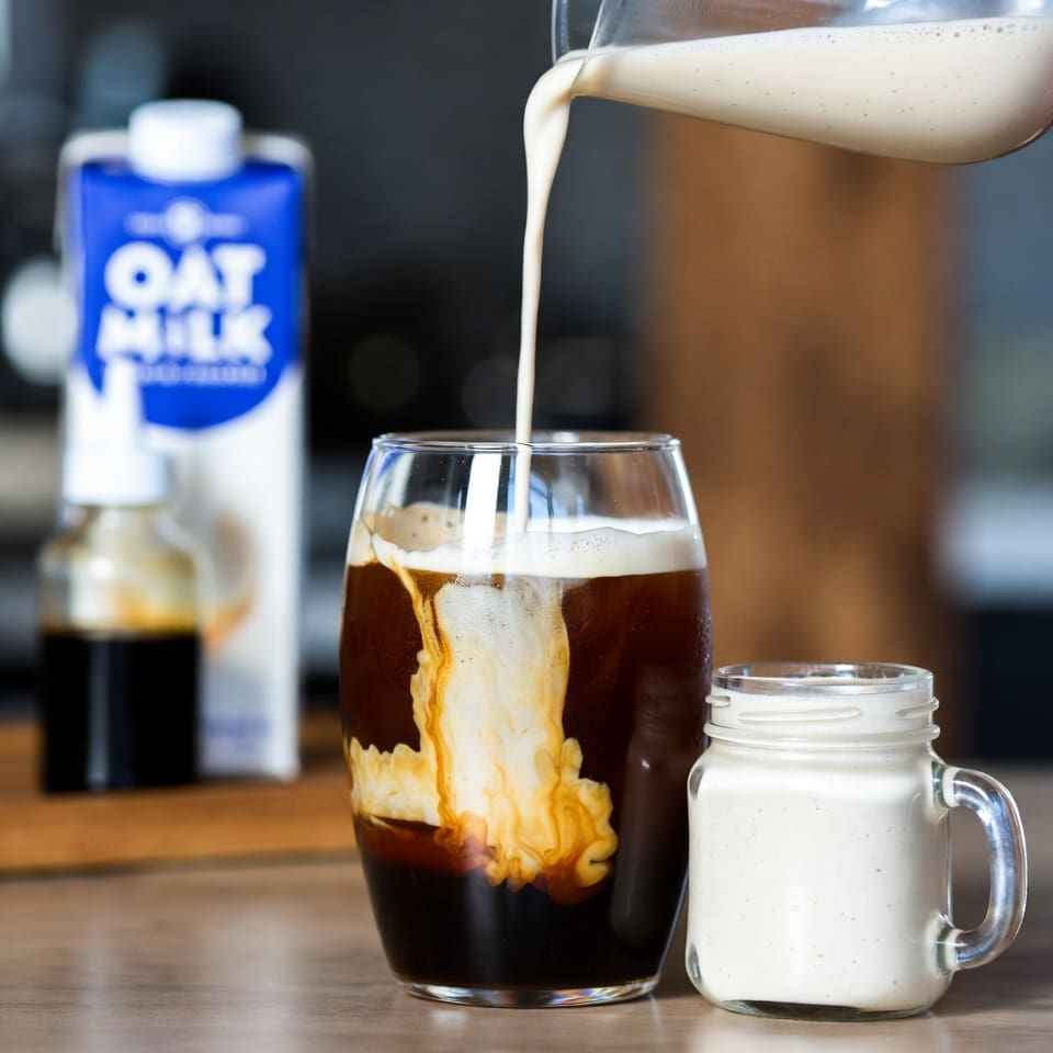 Finished dairy-free oat milk sweet cream poured over iced cold brew coffee